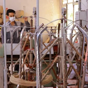 کار مردی با دستگاه نخ‌کشی در کارگاه سنتی