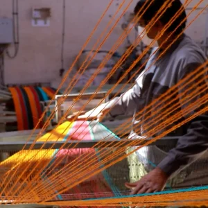 نمای باز از کار مرد با دستگاه نخ‌ریسی در کارگاه