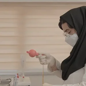 تکنسین آزمایشگاه با پوآر مقداری مایع برمیدارد