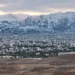 نمای هوایی رو به پایین از شهر و کوه های برفی