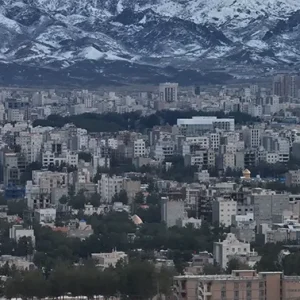 نمای هوایی شهر با چشم‌انداز کوه‌های برفی