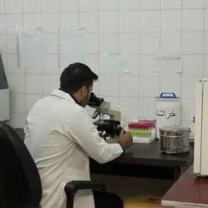 تصویر اپراتور آزمایشگاه درحال کار با میکروسکوپ کلینیک